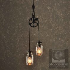 two mason jar chandeliers with lights hanging from them on a wall in a room