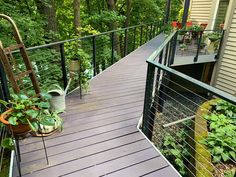 an outdoor deck with potted plants on the side and stairs leading up to it