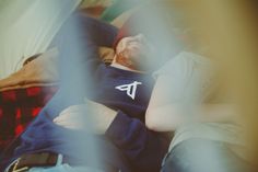 a man laying on top of a bed next to a red blanket and pillow with the letter t on it