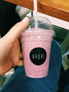 a person holding up a pink drink with a straw in it's cup and the words kauai written on it