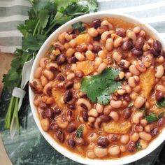 a white bowl filled with beans and cilantro on top of a green table