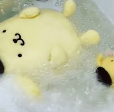 there is a teddy bear in the bathtub with bubbles and soap on it's side