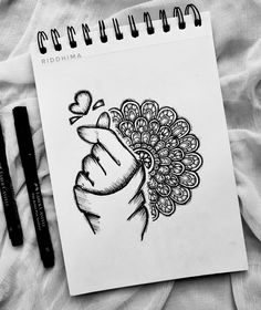 a drawing of a hand holding a flower with a heart on it and a pen next to it