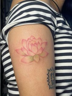 a woman's arm with a pink flower tattoo on her left shoulder and chest