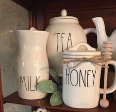 two white teapots sitting on top of a wooden shelf