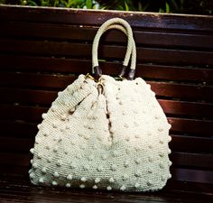 a white purse sitting on top of a wooden bench