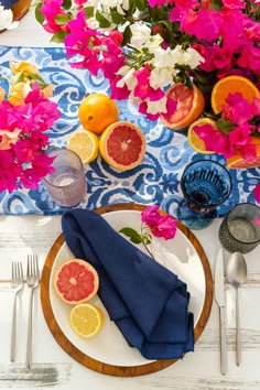 a plate with grapefruits, oranges and lemons on it next to silverware