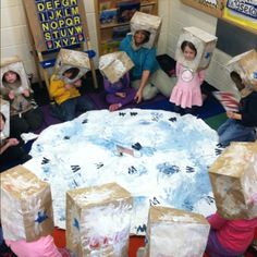 children are sitting on the floor with paper bags over their heads and boxes in front of them