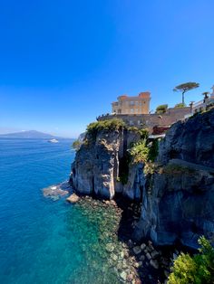 the ocean is clear and blue with some buildings on it's cliff face in the distance