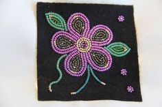 a close up of a flower on a black piece of cloth with bead work