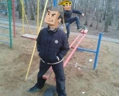 two men in black jackets and yellow safety goggles standing next to each other on a playground