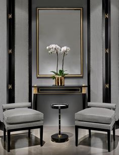 two chairs and a table in front of a large mirror with flowers on the table