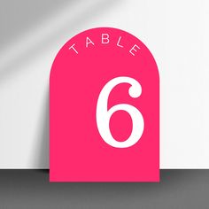 a pink table number with the number six in white on it's front and back