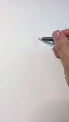 a person holding a pencil in their left hand and writing on paper with the other hand