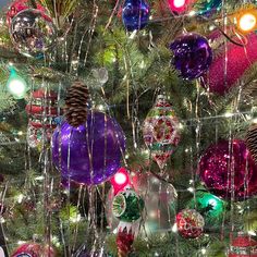 a christmas tree with ornaments and lights on it's branches is decorated in bright colors