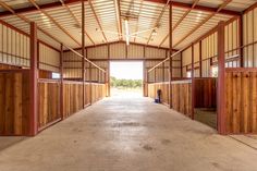 an empty horse barn with stalls and doors open