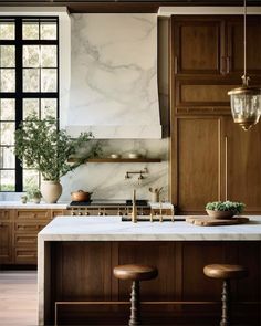 a kitchen with marble counter tops and wooden cabinets, two stools on the island