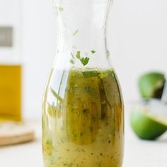 a glass pitcher filled with liquid sitting on top of a table next to sliced apples