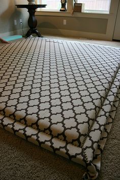 a bed with a black and white comforter on it in front of a window