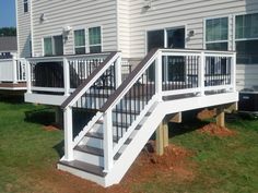 a white deck with stairs and railings in front of a house