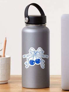 a water bottle sitting on top of a wooden table next to a cup and pen