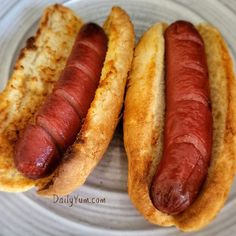 two hot dogs on buns sitting on a plate