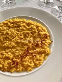 a white plate topped with macaroni and cheese next to two glasses of wine