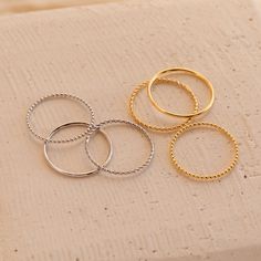 Our Skinny Stacking Rings are the simple and minimalist essentials for creating a dainty, multilayered finger stack that'll be the envy everyone around you. Their slightly textured finish adds a unique touch to the stack, as the trio features a ball, twist, and smooth band. Material: High-Quality Solid 925 Sterling Silver Finish: Sterling Silver ∙ 18K Gold Dimensions: 1mm This listing is for a set of 3 rings: 1 SOLID ring, 1 TWISTED ring, and 1 BEADED ring SKU: RR-RR051 Sizing Guide Rings are cr Gold Minimalist Stackable Rings For Layering, Minimalist Stackable Rings For Layering, Gold Stacked Midi Rings Minimalist Style, Gold Stacked Minimalist Midi Rings, Minimalist Stacked Midi Rings As Gift, Minimalist Stacked Gold Midi Rings, Adjustable Minimalist Stackable Rings, Stacked Midi Rings For Everyday, Trendy Tarnish-resistant Stackable Rings