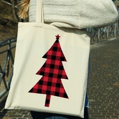 a woman carrying a red and black plaid christmas tree tote bag