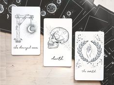 four cards with different designs on them sitting on top of a wooden table in front of a black and white background