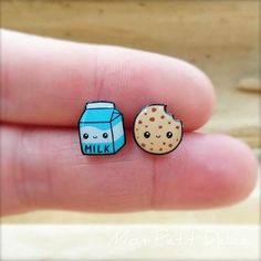 a person holding two small pins with milk and cookies on them