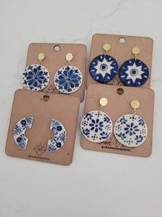 three pairs of blue and white ceramic earrings on brown tags with gold earring clips