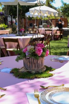 a wooden basket filled with pink flowers on top of a table covered in green grass