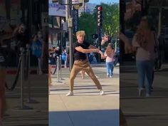 the man is practicing his moves on the city street while people are walking by in the background