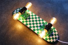 a green and white skateboard with two lights on it's end laying on the ground