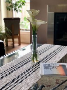 there is a vase with flowers in it on the table next to a book and coffee table