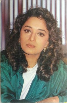 an old photo of a woman with long hair and wearing a green jacket, looking at the camera