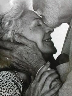 an older couple kissing each other while standing next to each other