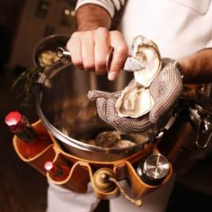 a person holding a metal pot filled with oysters