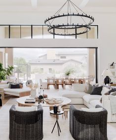 a living room filled with lots of furniture and a chandelier hanging from the ceiling