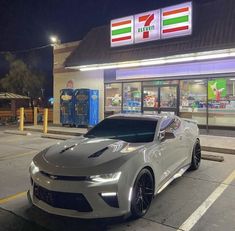 a silver chevrolet camaro parked in front of a gas station with the italian flag on it