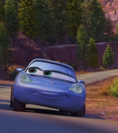 a blue car driving down a road next to trees