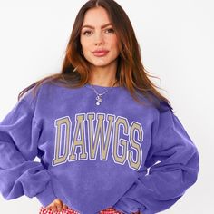 This Washington Huskies Comfort Colors Sweatshirt is perfect for any Huskies football fan looking for a cozy and stylish way to show their team spirit. Whether it's game day or a tailgate event, this 'Dawgs' sweatshirt is a must-have. The ribbed collar, cuffs, and bottom hem ensure a well-fitted sweatshirt is comfortable to wear all day long. The relaxed fit and sewn in twill label add to the overall quality of this sweatshirt, making it a great gift for any Huskies fan. COLORS: Violet (worn-in Sports Fan Crew Neck Top With Mascot, Crew Neck Mascot Top For Fan Gear, Varsity Crew Top For Fan Gear, Mascot Crew Neck Top For Fan Gear, Fan Apparel Crew Neck Top With Mascot, Crew Neck Tops With Mascot For Fan Gear, Relaxed Fit Sweatshirt For College Football Season, Sporty Mascot Crew Neck Tops, College Football Season Mascot Tops