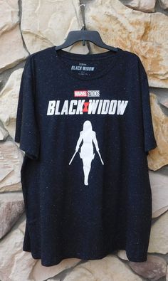 a black widow t - shirt hanging on a stone wall