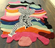 colorful rugs are laid out on the floor in front of a wooden table with an animal - print design