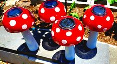 three red and white mushrooms sitting on top of each other in front of a garden