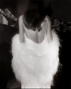 black and white photograph of a woman dressed in an angel costume, with her back to the camera