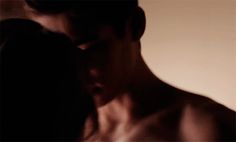 a blurry image of a shirtless man and woman kissing in front of a wall