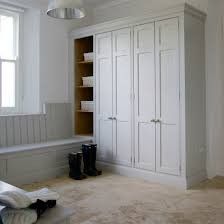 an empty room with white cupboards and boots on the floor