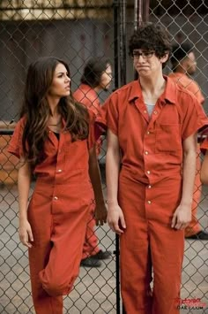 two people in orange prison uniforms standing next to each other